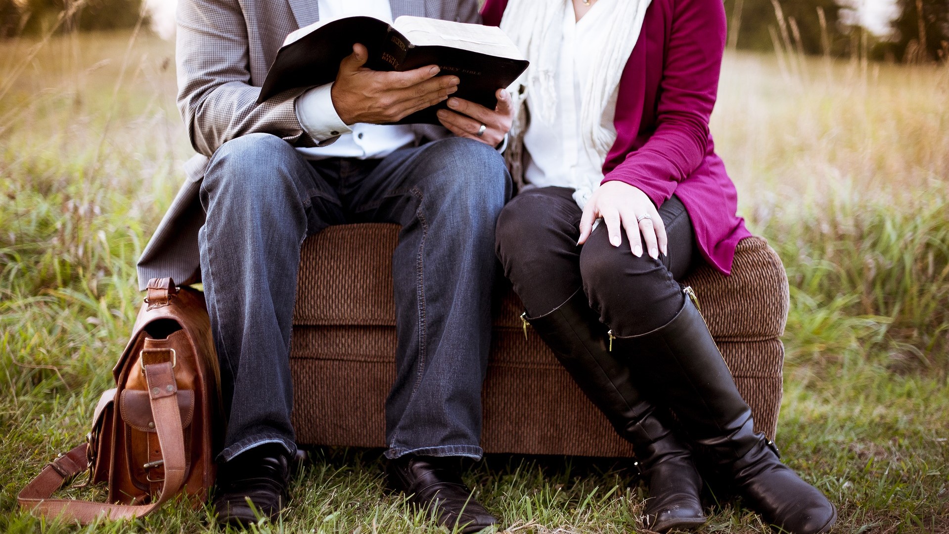 草原のソファに座り一緒に本を読む夫婦
