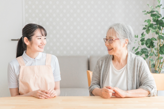 笑顔で会話する高齢女性と介護スタッフ