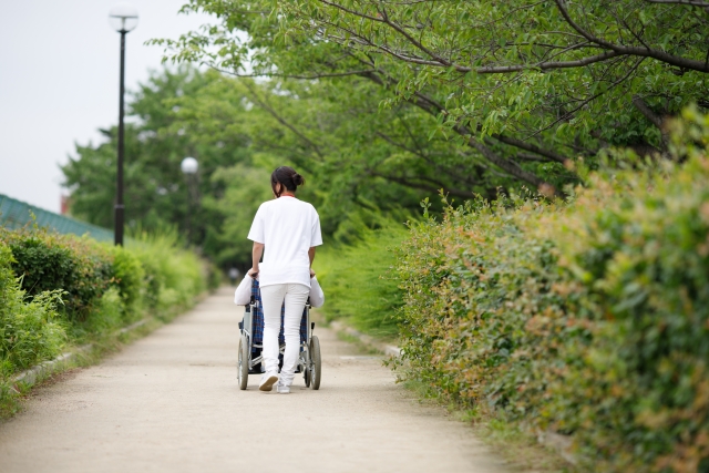 車椅子で散歩する高齢者と介護士
