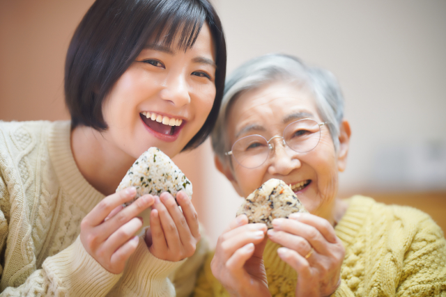 おにぎりを食べながら笑う祖母と孫