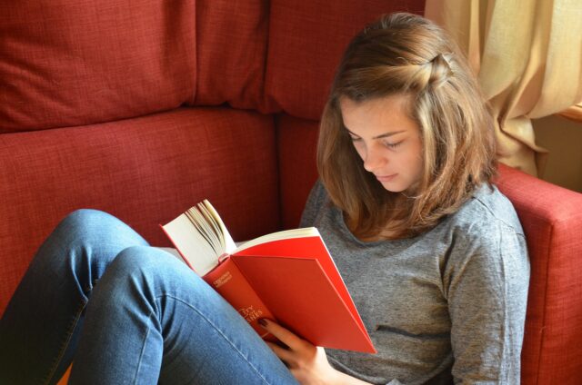 ソファで本を読む若い女性