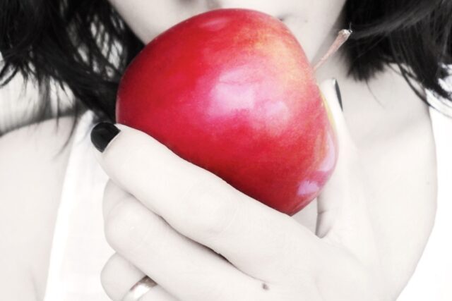 真っ赤なリンゴを食べようとする女性